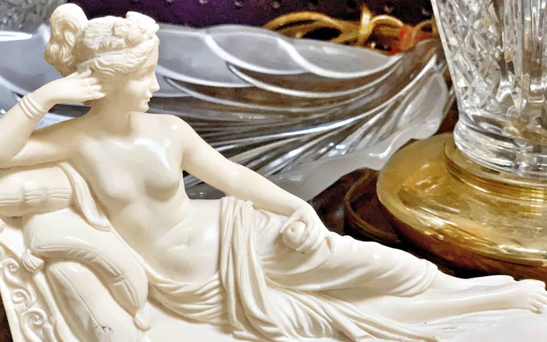Carved marble reclining figure statue beside crystal at The Antique Gallery of Houston in Spring, Texas
