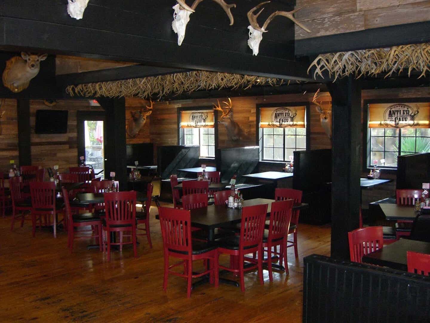Dining room with red chairs and rows of antlers wired along the ceiling beams at Richter's Antler Cafe in Spring Branch, Texas