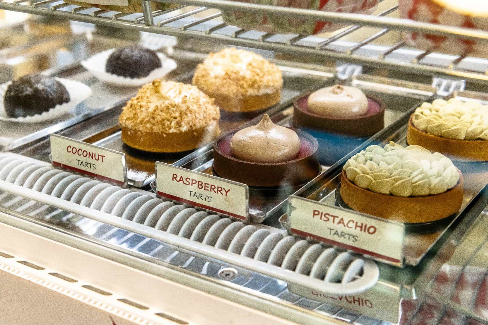 Coconut, raspberry and pistachio tarts in the dessert case at Ari's Pantry in Dallas