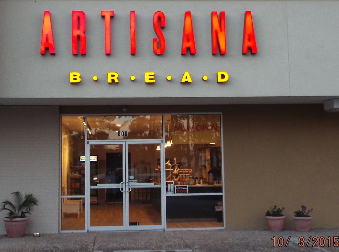 The red Artisana Bread sign above the shop entrance in Houston, Texas