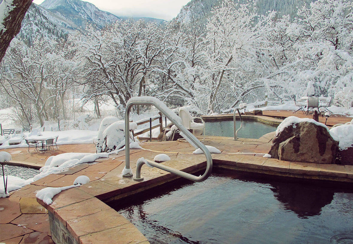 Steaming natural hot springs pool in snow below Mount Sopris at Avalanche Ranch, Colorado