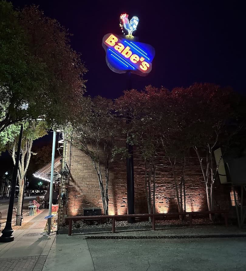 Babe's Chicken Dinner House neon sign glowing at night in downtown Roanoke, Texas