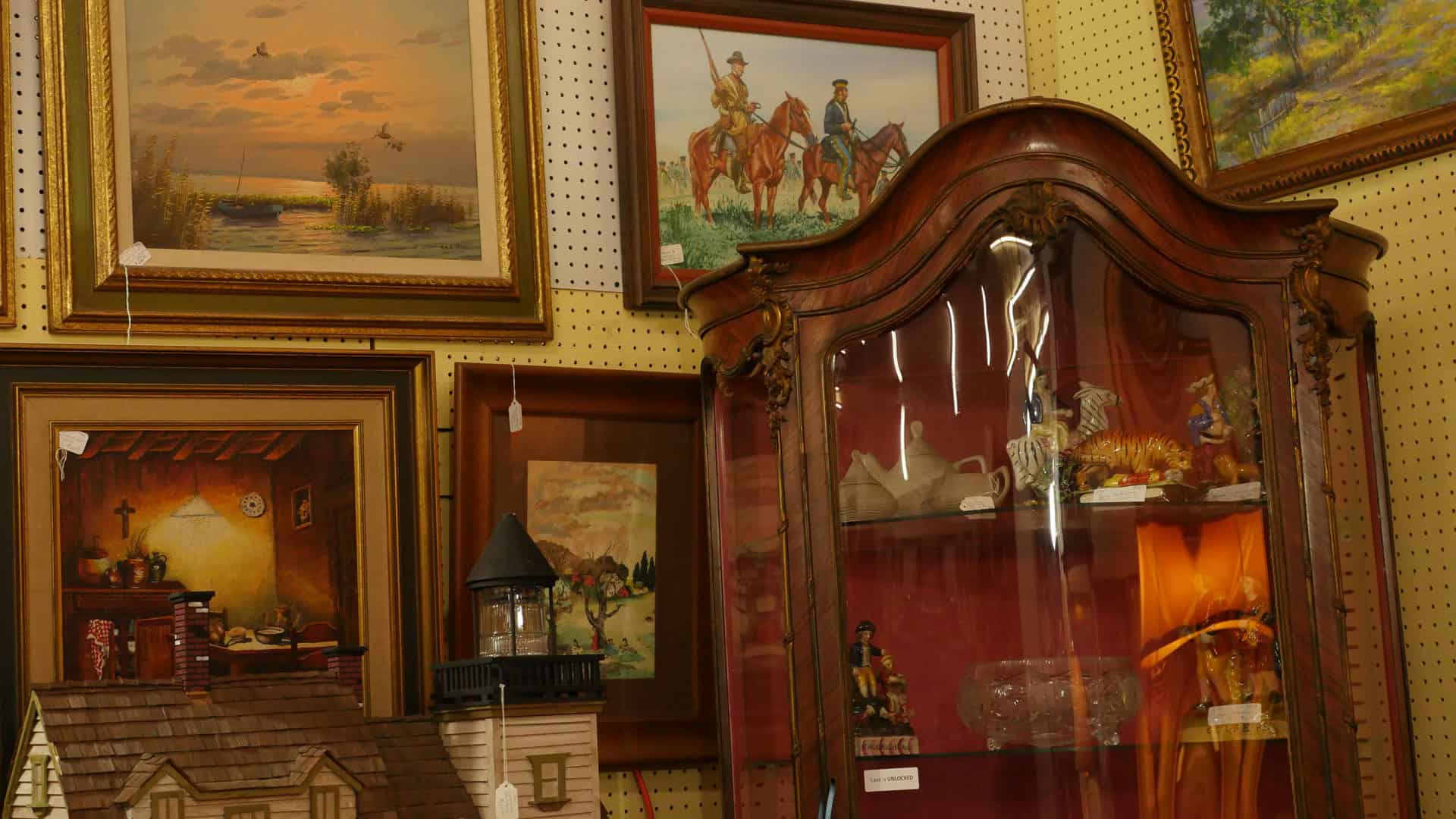 Antique armoire and framed art in a booth at Benbrook Antique Mall in Benbrook, Texas