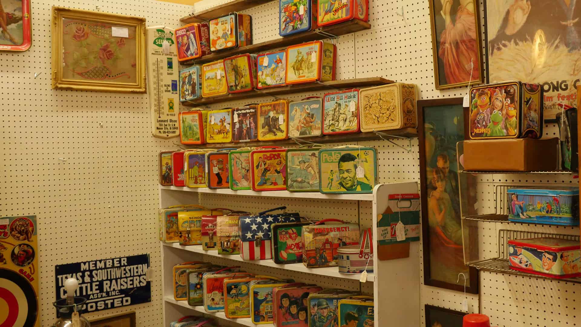 Booth wall of framed art and vintage signs at Benbrook Antique Mall in Benbrook, Texas