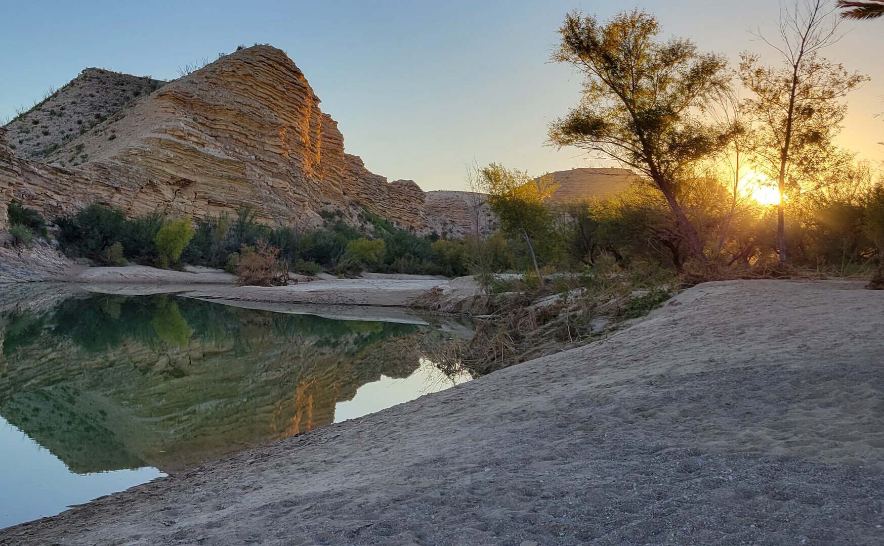 Golden sunset over a limestone cliff reflected in the Rio Grande at Big Bend