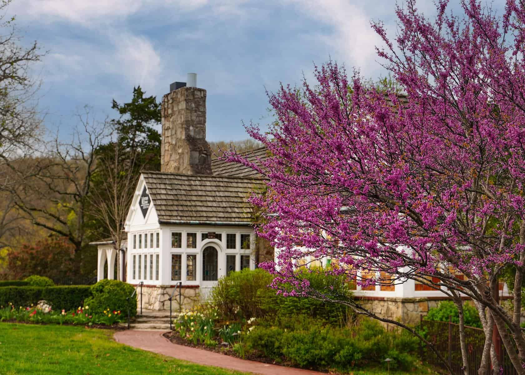 Charming white cottage with a stone chimney at Big Cedar Lodge in Missouri