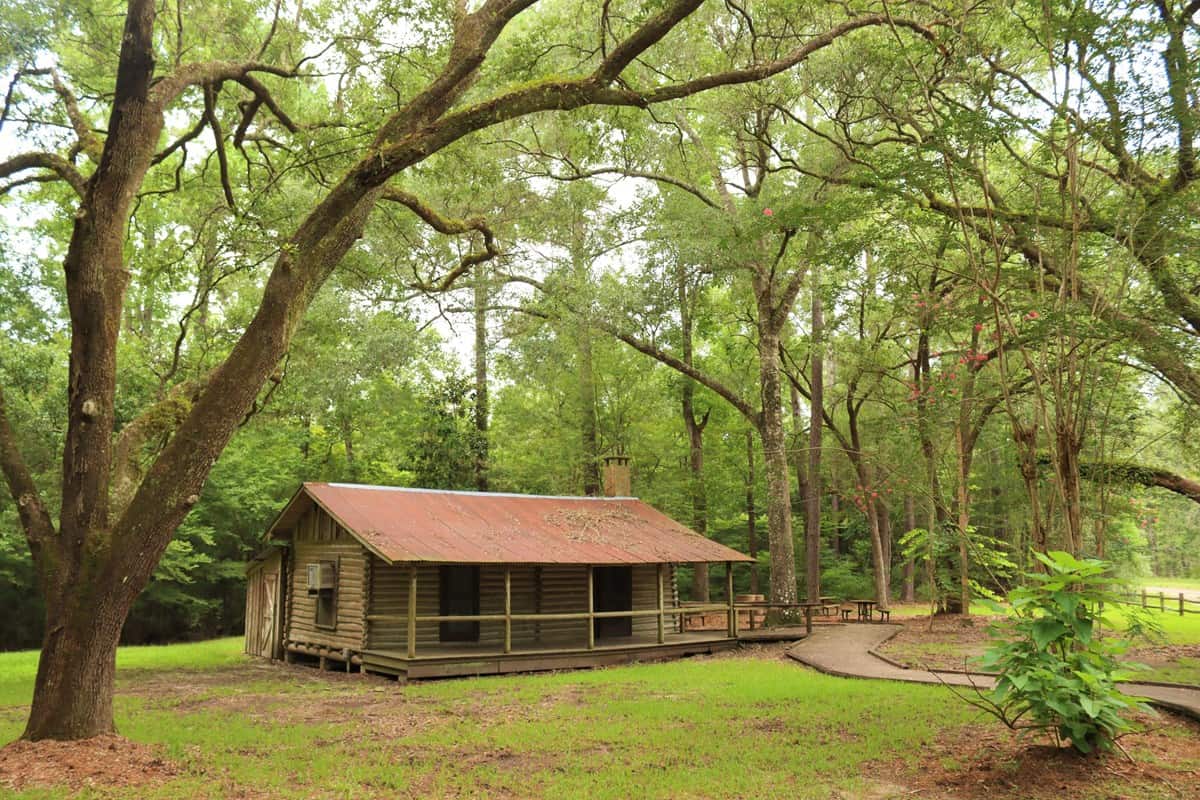 Rustic cabin shaded by tall oaks at Big Thicket National Preserve, Texas