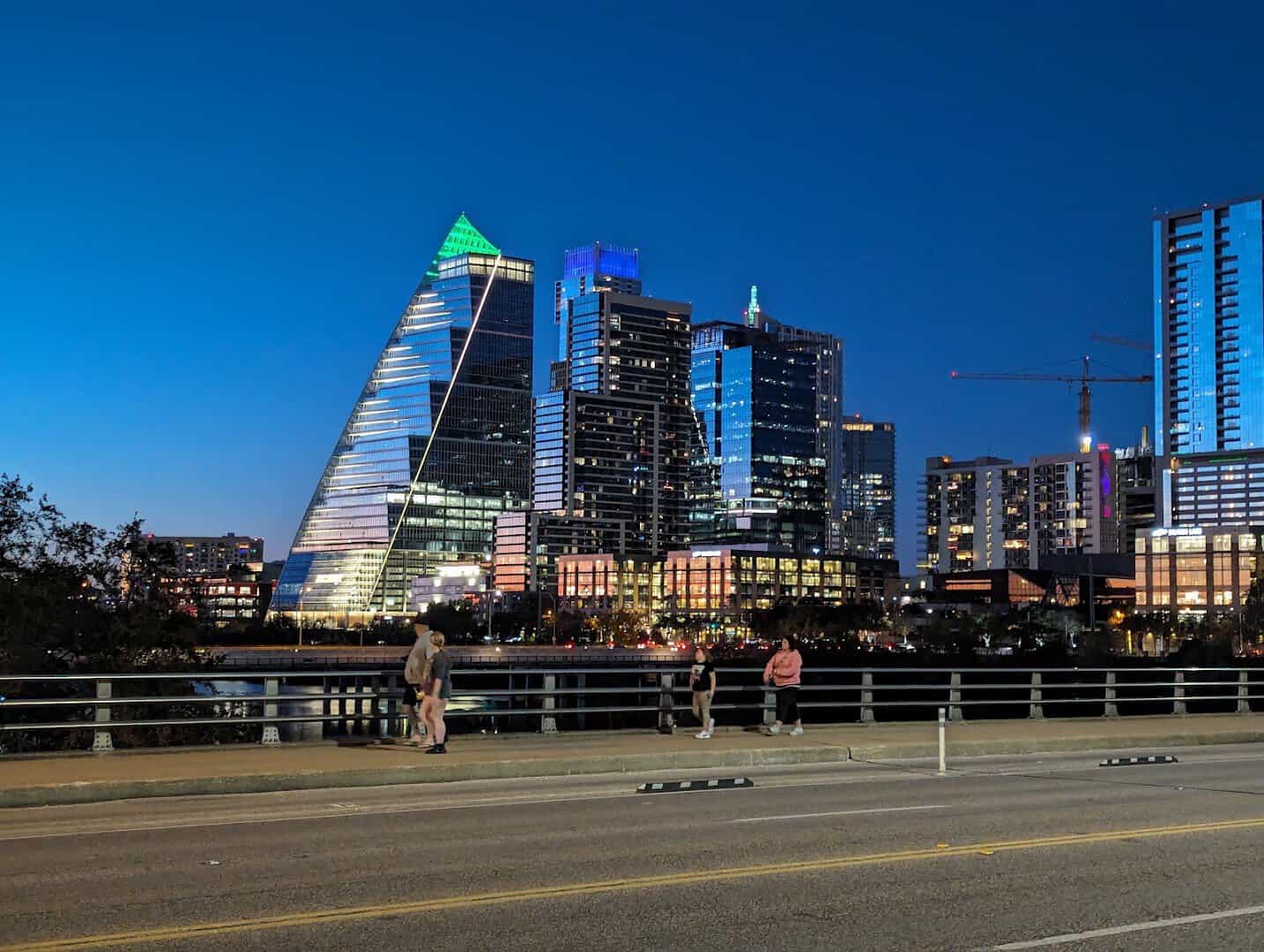 The Congress Avenue Bridge sidewalk at blue hour with the Austin skyline behind it