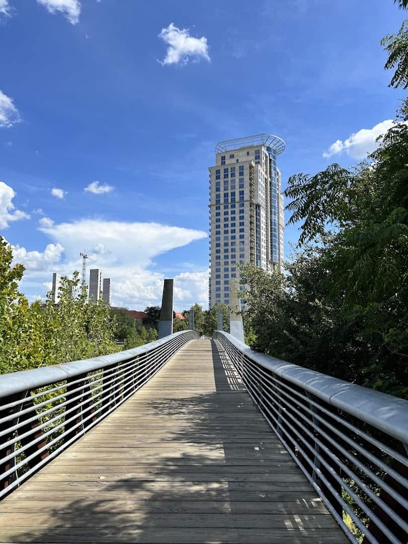 Paved Buffalo Bayou Park trail with the downtown Houston skyline beyond the trees