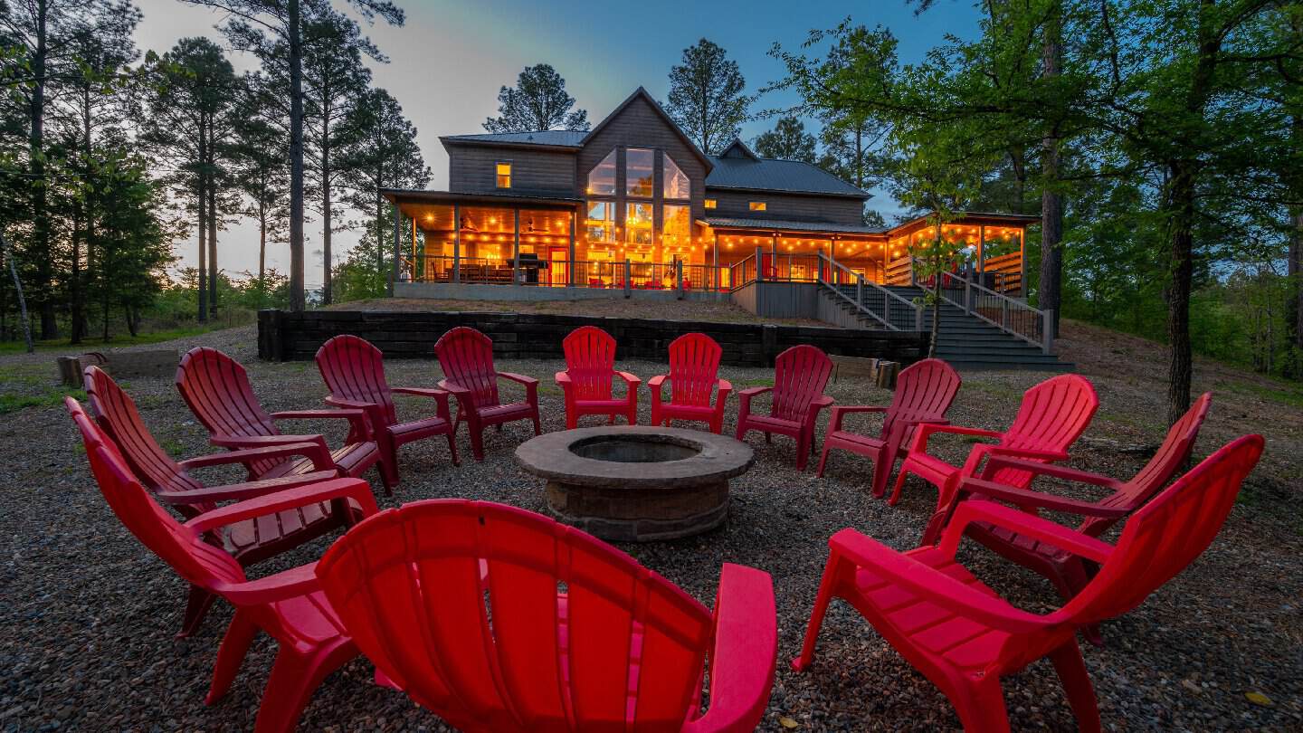 Cabin at dusk with a fire pit and chairs among the pines at Beavers Bend Creative Escapes in Broken Bow, Oklahoma