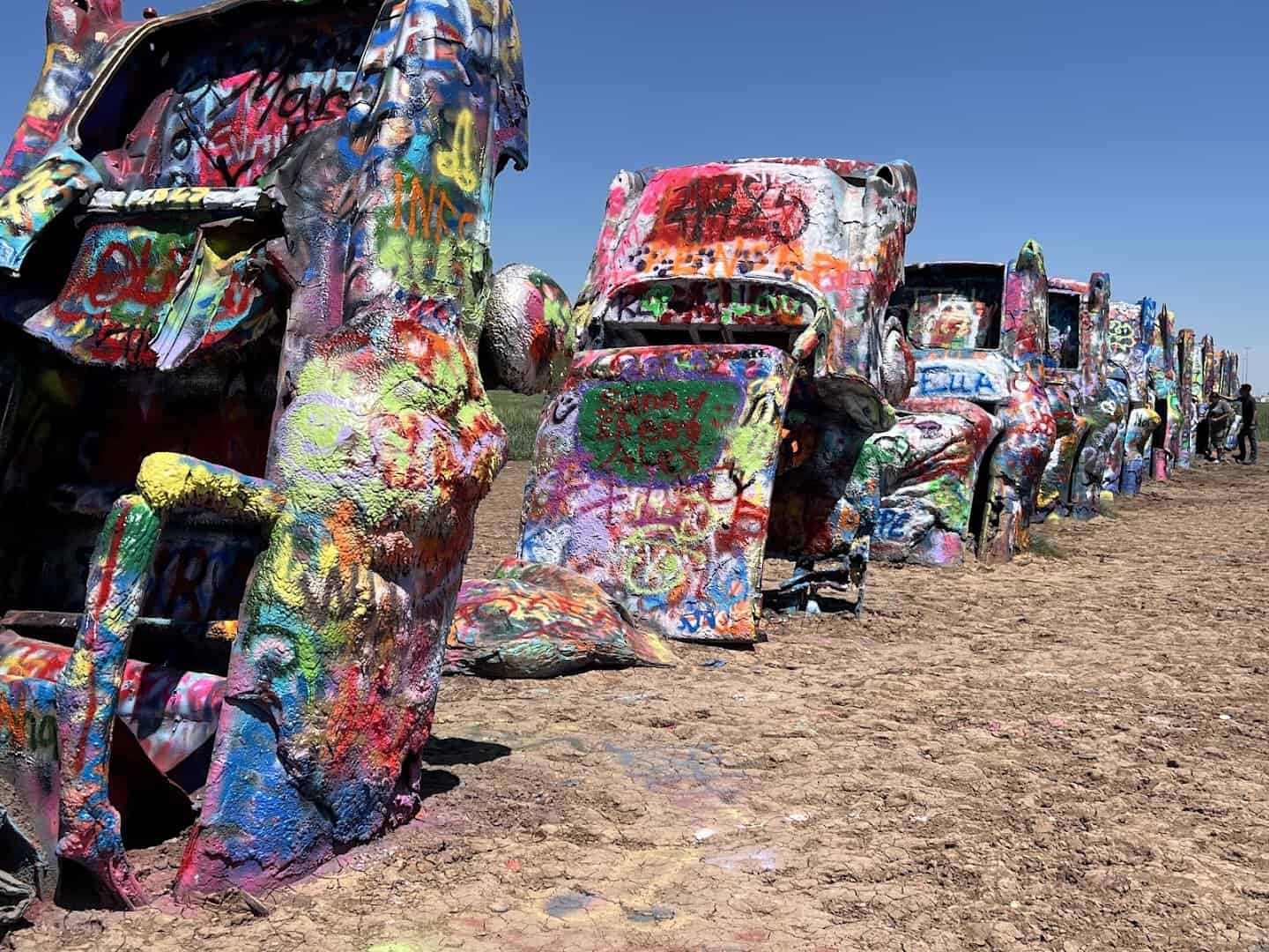 Spray-painted half-buried Cadillacs in a row at Cadillac Ranch in Amarillo, Texas
