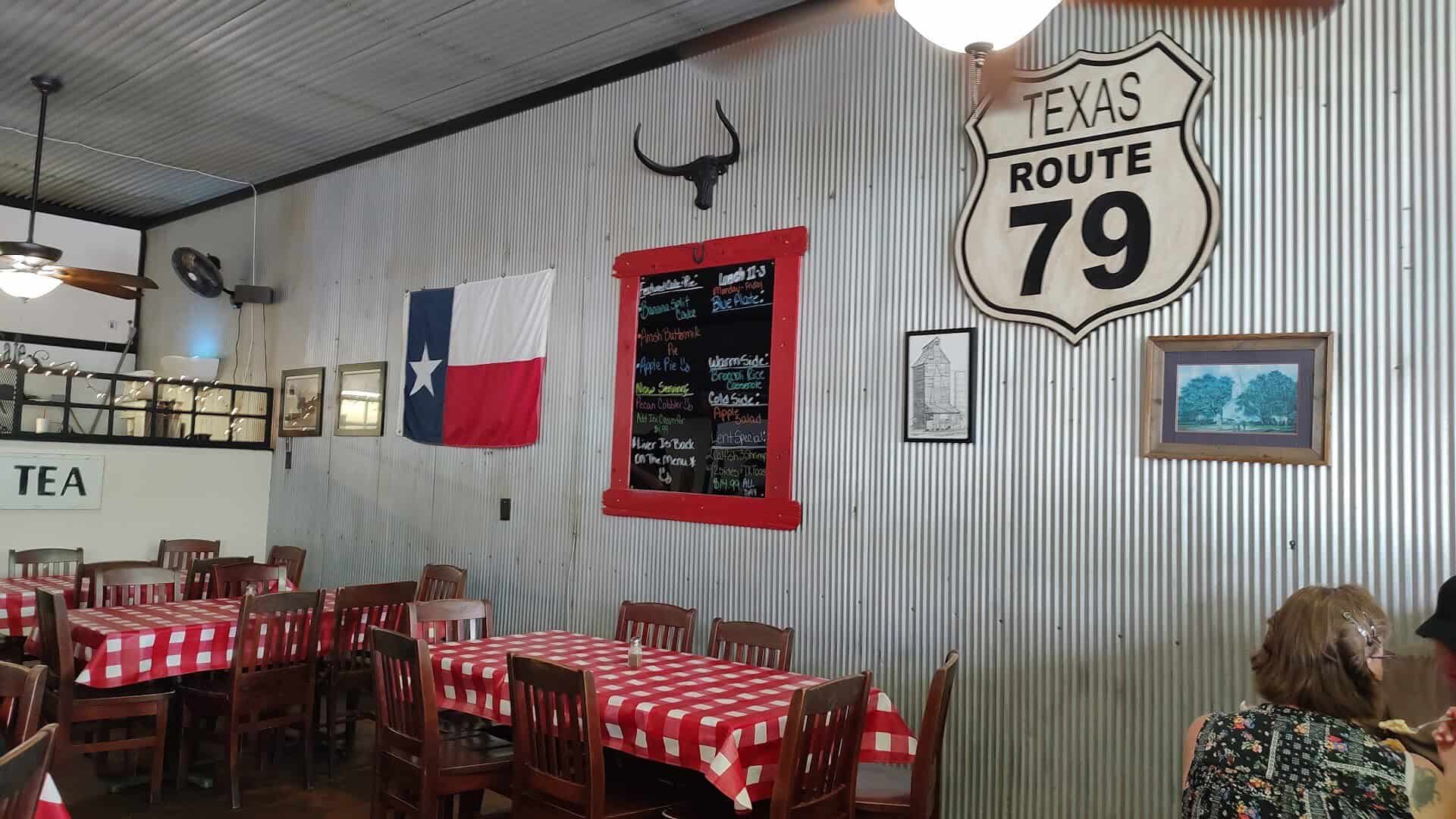 Country dining room with a Texas flag and Route 79 sign at Texan Cafe and Pie Shop in Hutto, Texas