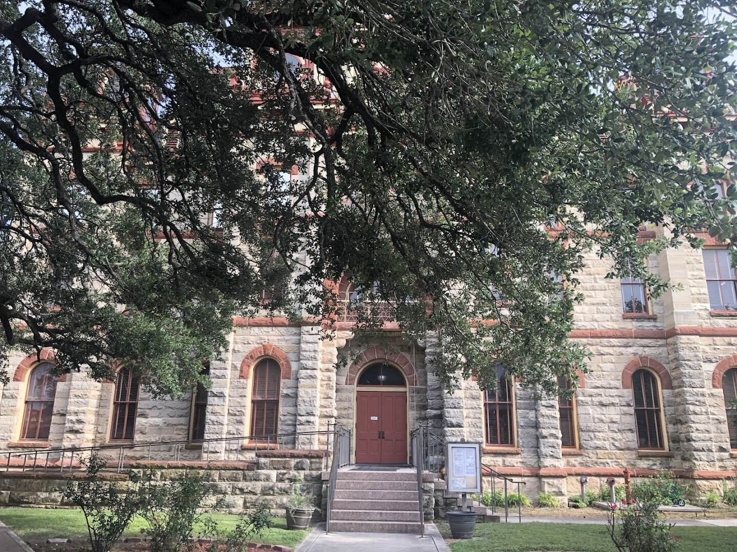 Caldwell County Courthouse framed by live oak branches in Lockhart, Texas