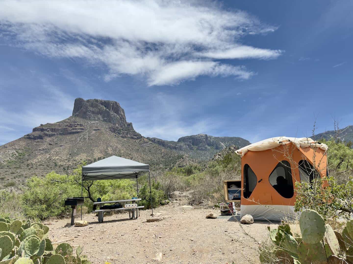 Campsite with tent, picnic shelter and grill at Chisos Basin Campground beneath Casa Grande