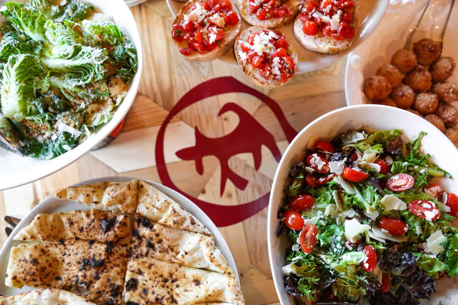 A spread of pizzas and salad at Cane Rosso in Dallas