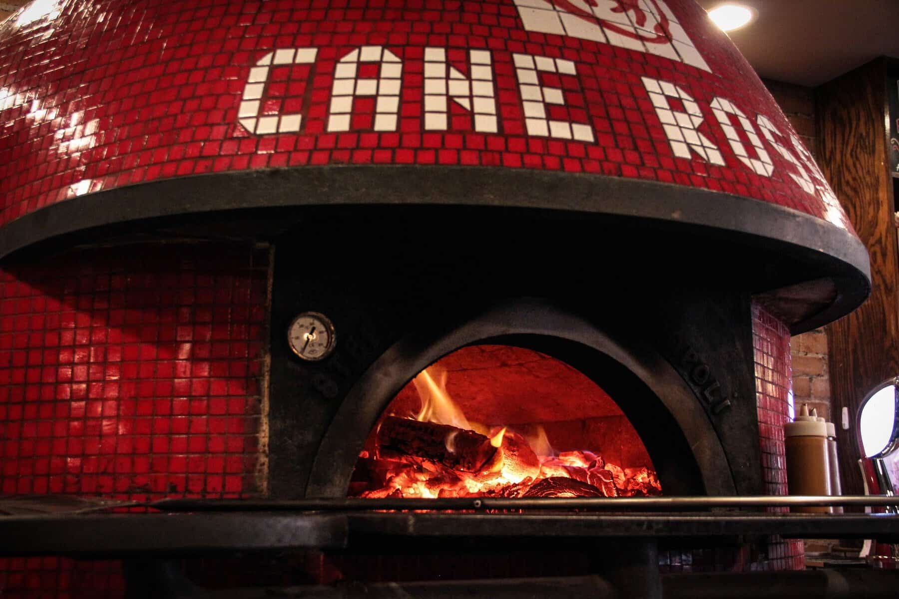 Wood-fired oven with flames at Cane Rosso in Dallas