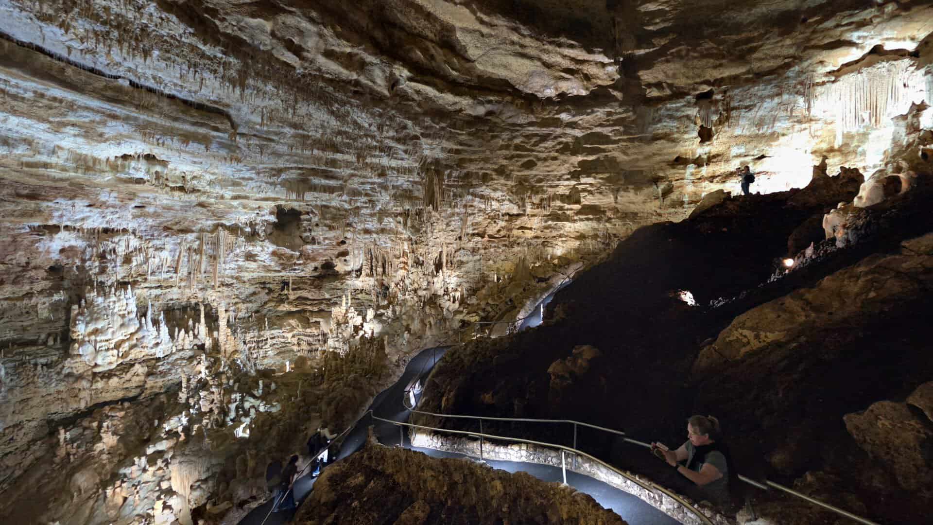 Lit walkway winding past formations on a cave tour at Natural Bridge Caverns