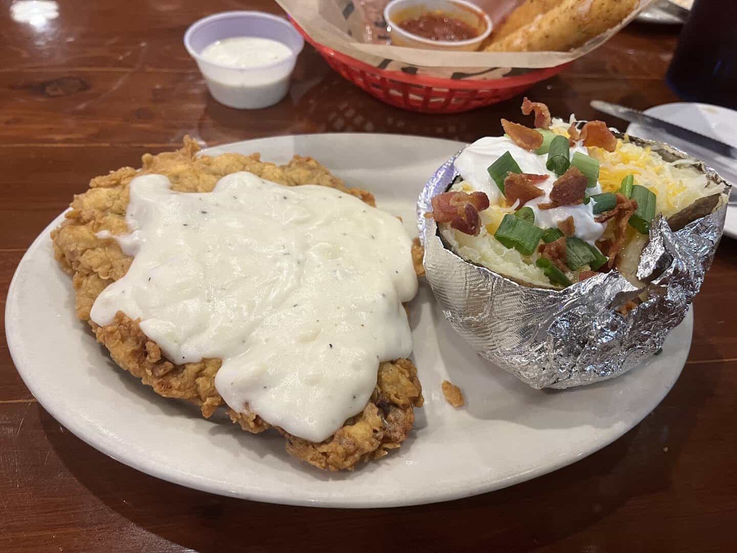 Chicken fried steak with cream gravy and a loaded baked potato at Hofbrau Steaks in Porter, Texas
