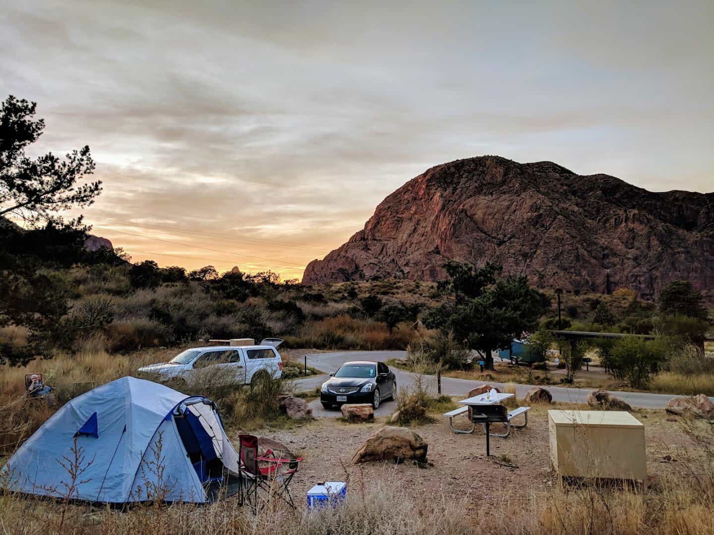 Tents and vehicles at Chisos Basin Campground under a fading evening sky