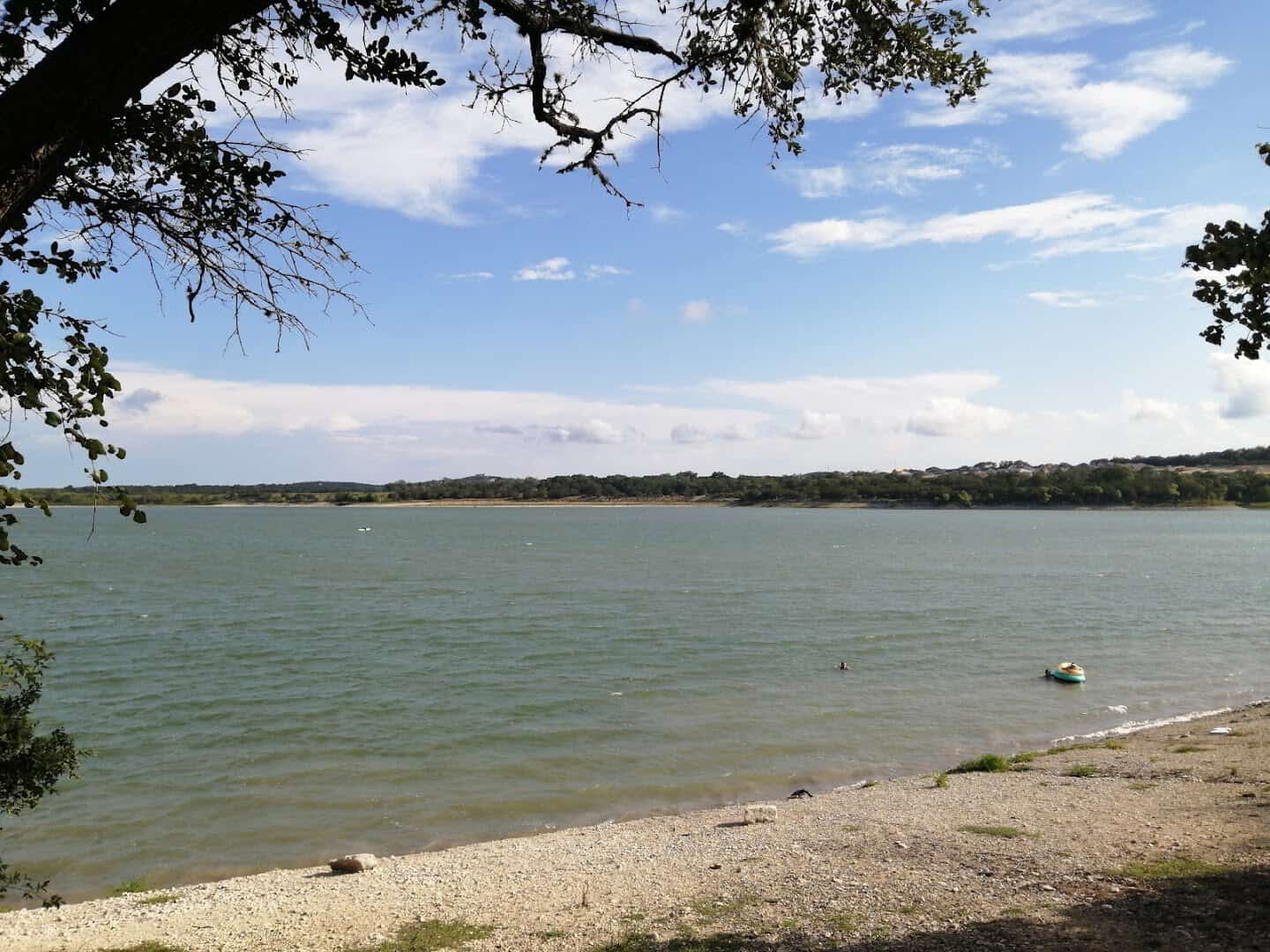 Clear shallow water along the pale gravel shoreline of Boerne City Lake in Boerne, Texas