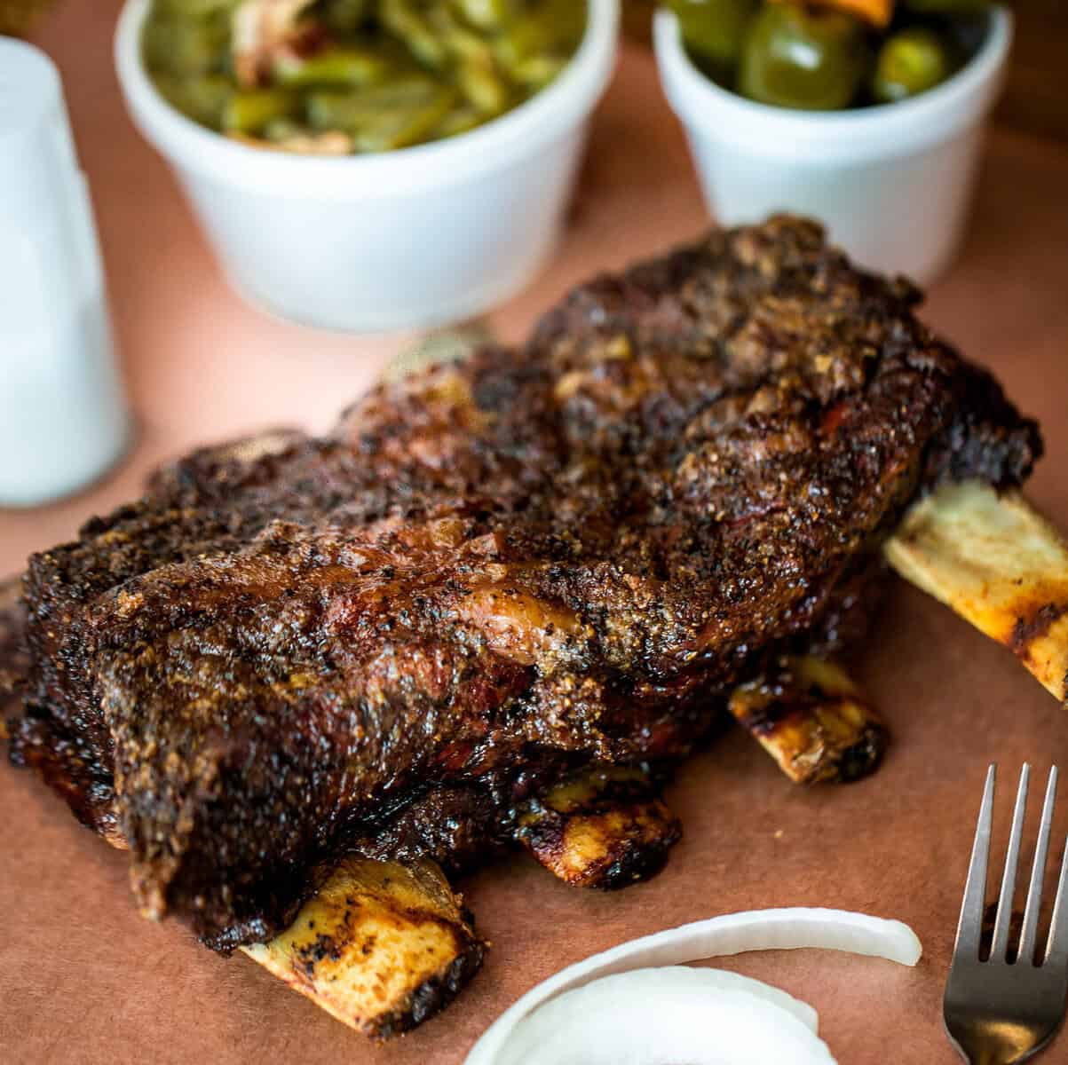 Giant smoked beef ribs served with green beans and jalapenos at Cooper's Old Time Pit Bar-B-Que in Austin