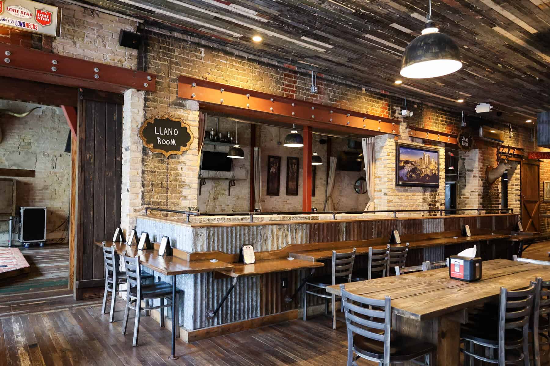 Rustic brick and wood interior with long communal tables in the Llano Room at Cooper's Old Time Pit Bar-B-Que in Austin