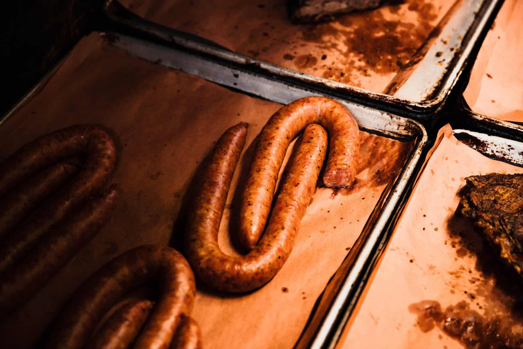 Coiled smoked sausage links cooking on the pit at Cooper's Old Time Pit Bar-B-Que in Austin
