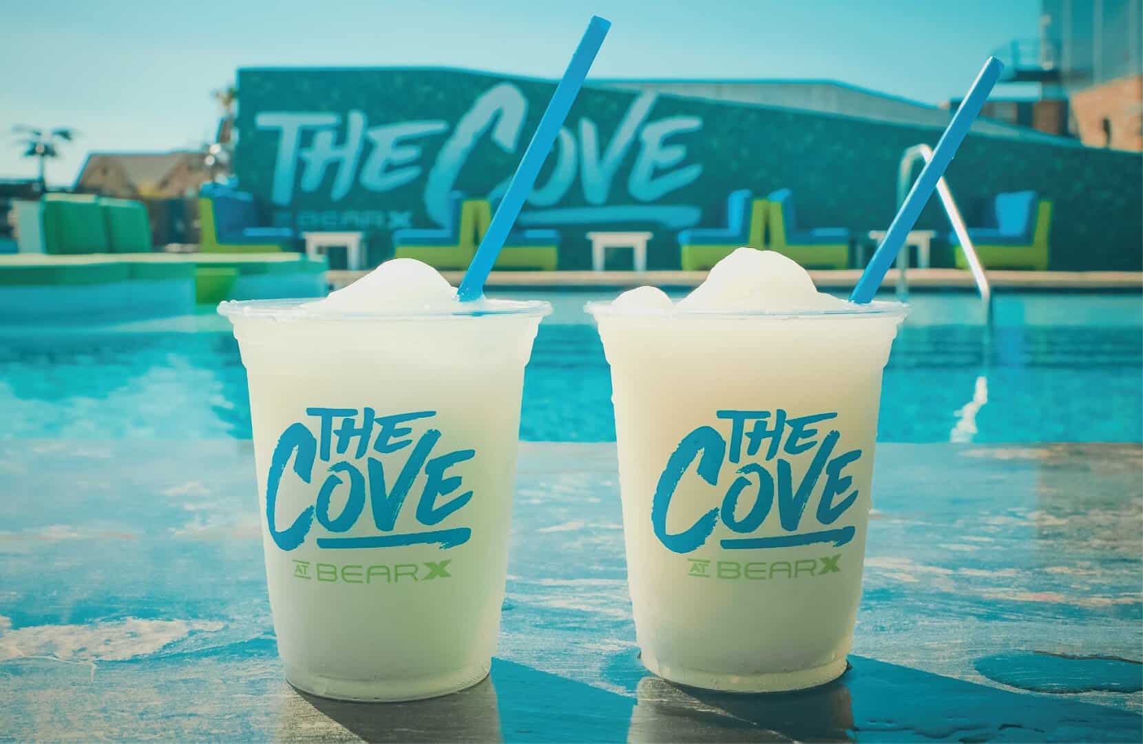 Two frozen drinks in The Cove cups beside the pool at The Cove at BearX in College Station, Texas