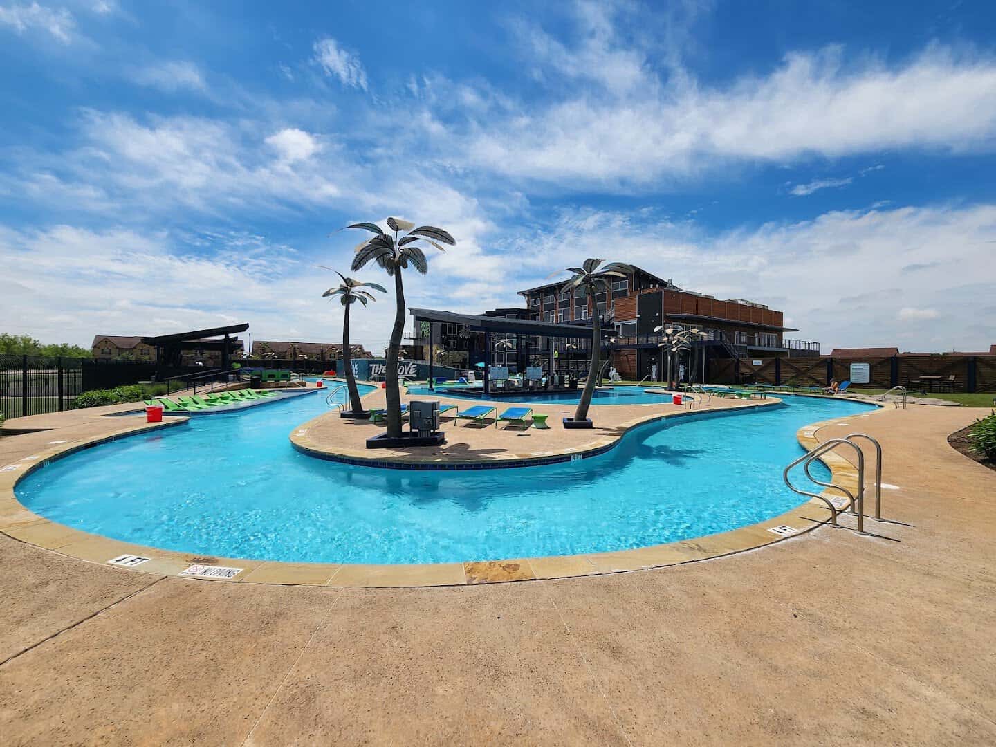 Lazy river winding past a palm island at The Cove at BearX in College Station, Texas