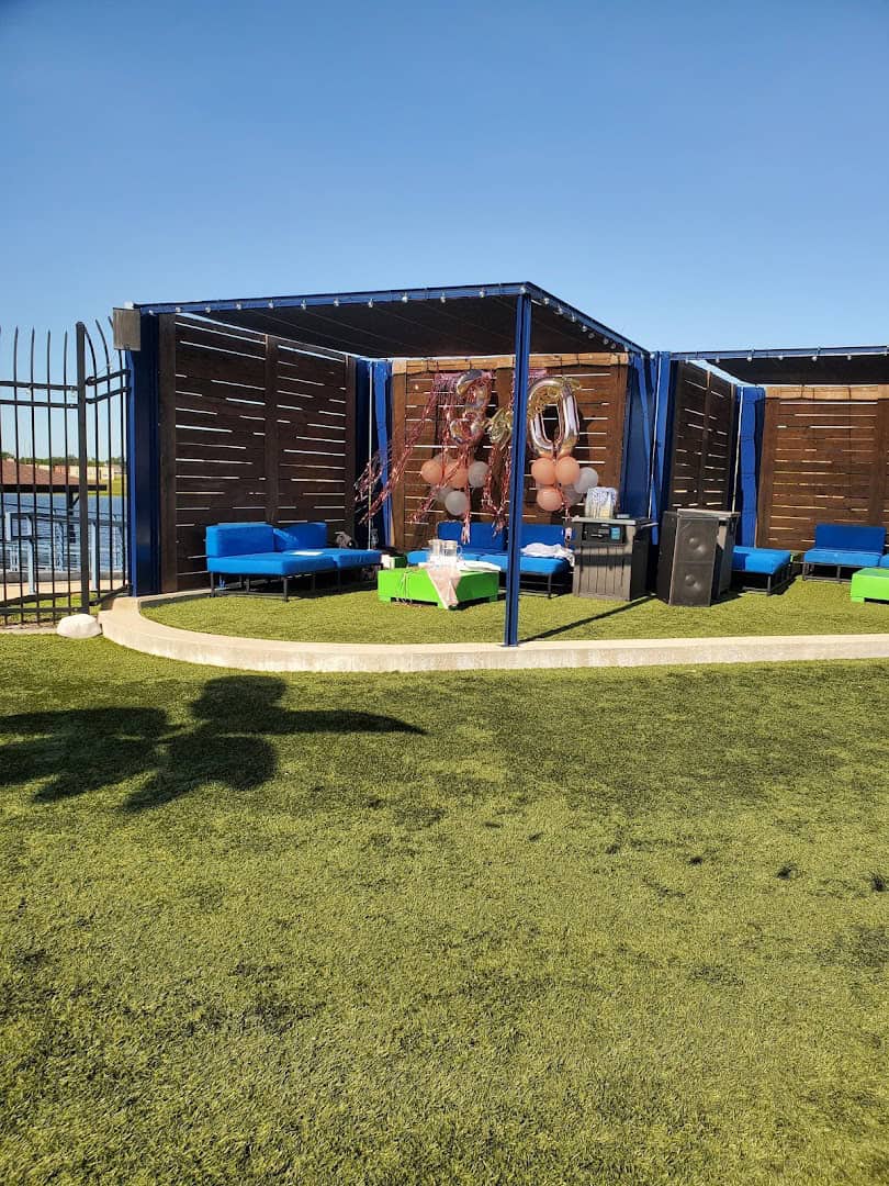 Shaded cabana with cushioned couches on the lawn at The Cove at BearX in College Station, Texas