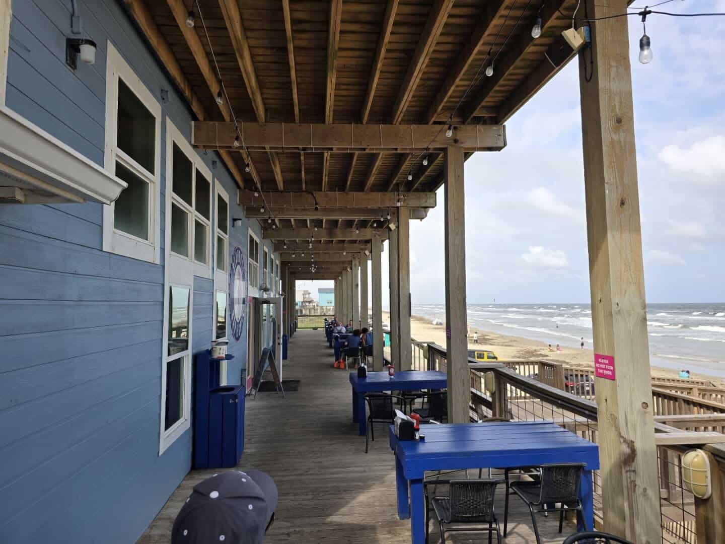 Covered deck with blue tables beside the Gulf at Seahorse Bar and Grill in Surfside Beach, Texas