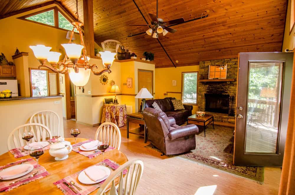 Cozy cabin great room with a fireplace and set dining table at Asheville Cabins of Willow Winds in Asheville, North Carolina