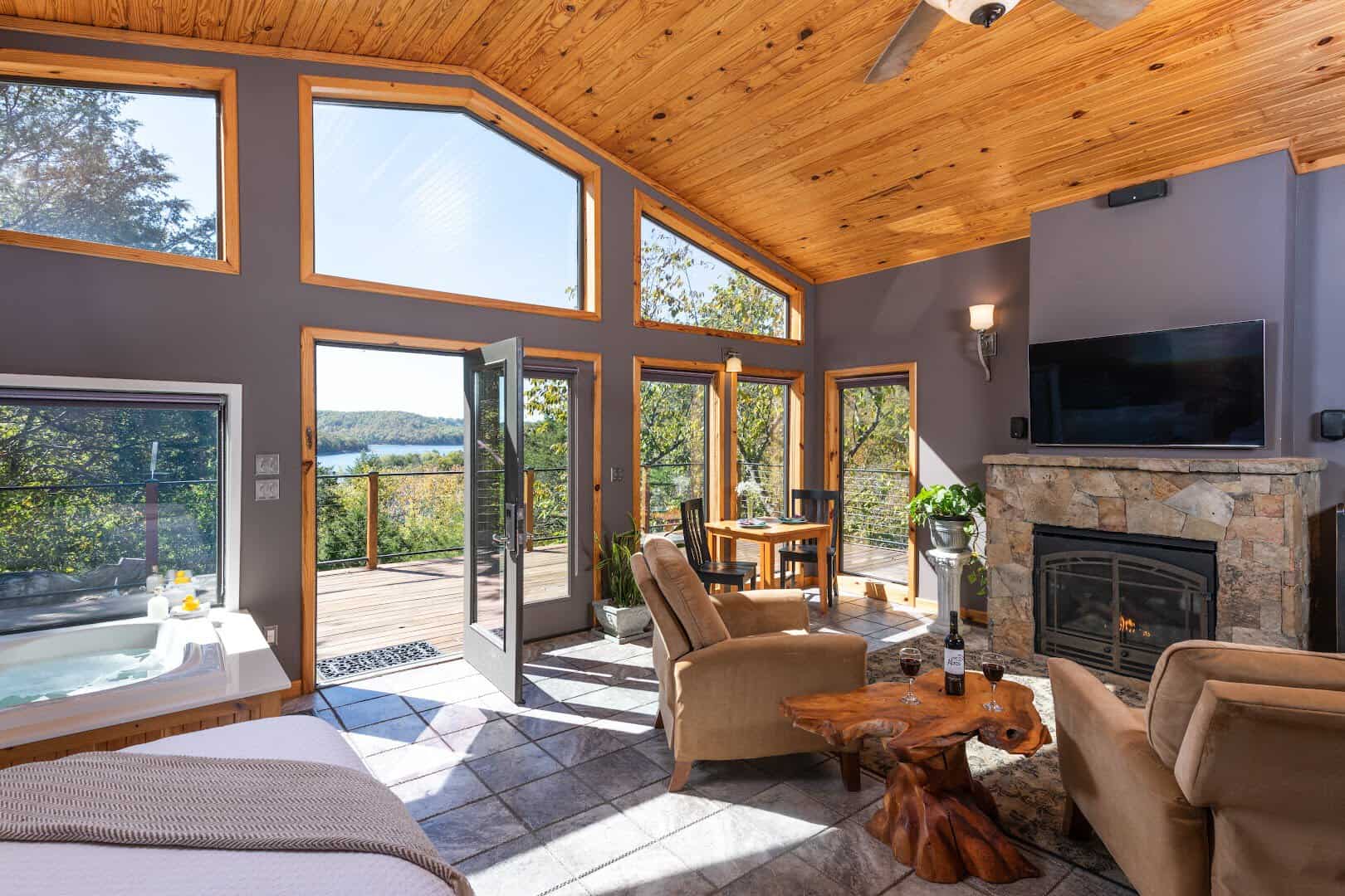 Cozy cabin great room with a stone fireplace and hot tub at Beaver Lakefront Cabins in Eureka Springs, Arkansas