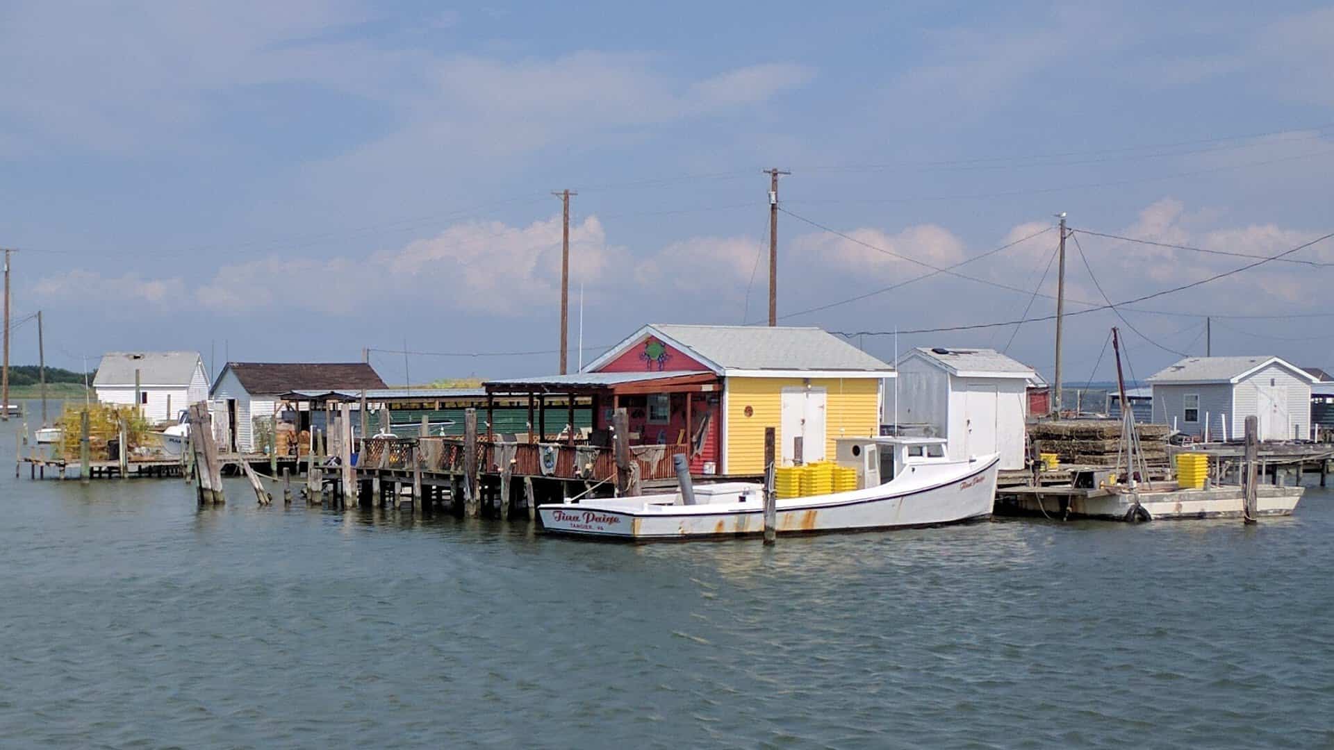 Wooden crab shanties on stilts over the water at Tangier Island, Virginia, with a workboat alongside