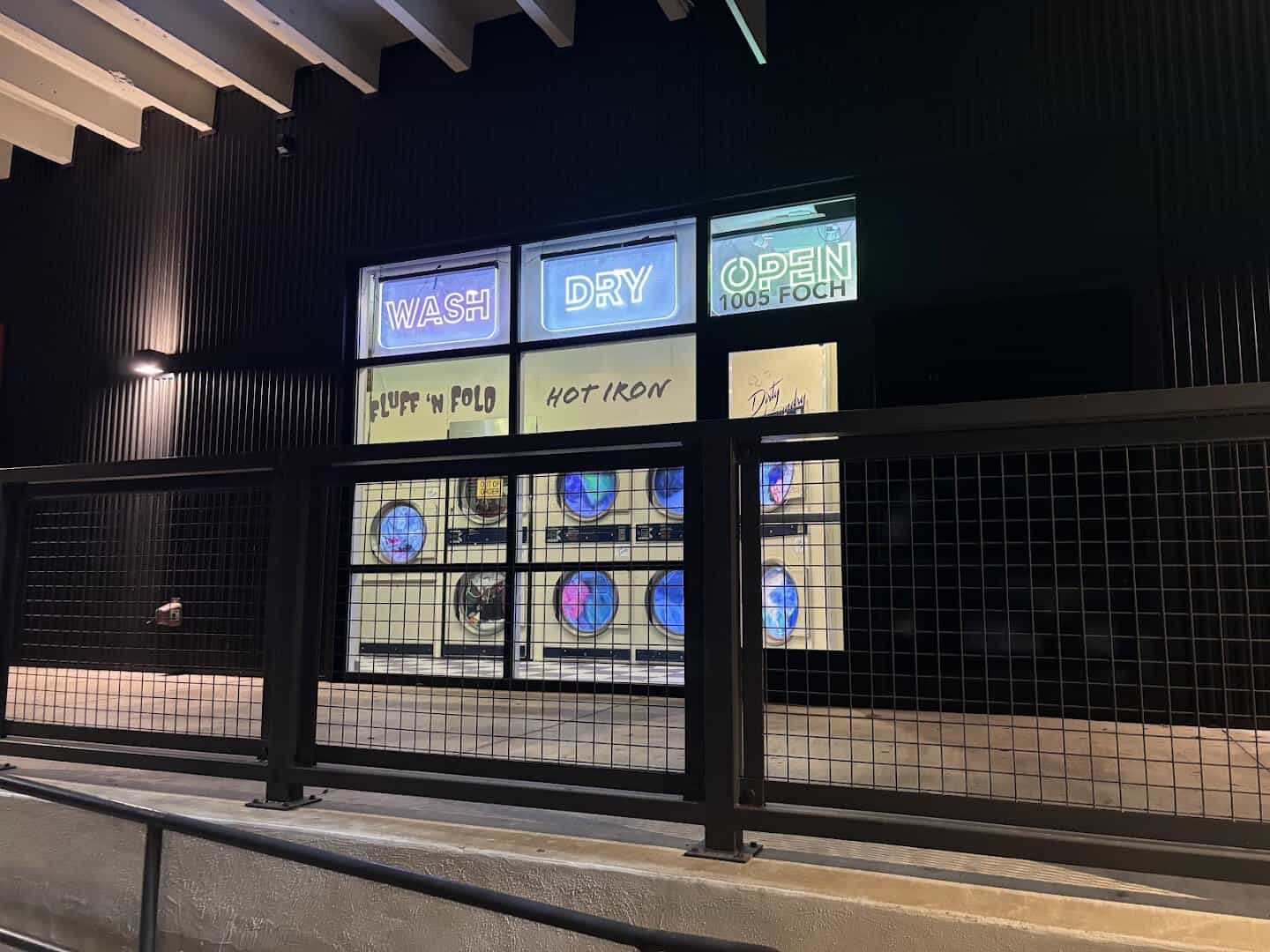 Exterior neon signs at night marking the Dirty Laundry laundromat entrance in Fort Worth