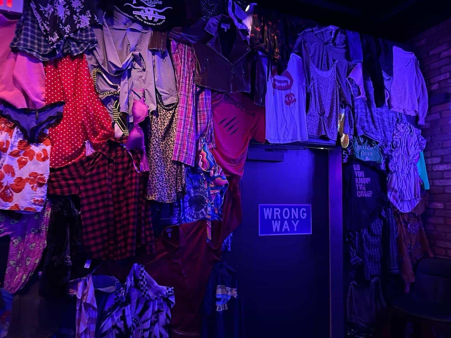 Clothes and garments hanging from the ceiling decor inside Dirty Laundry speakeasy in Fort Worth