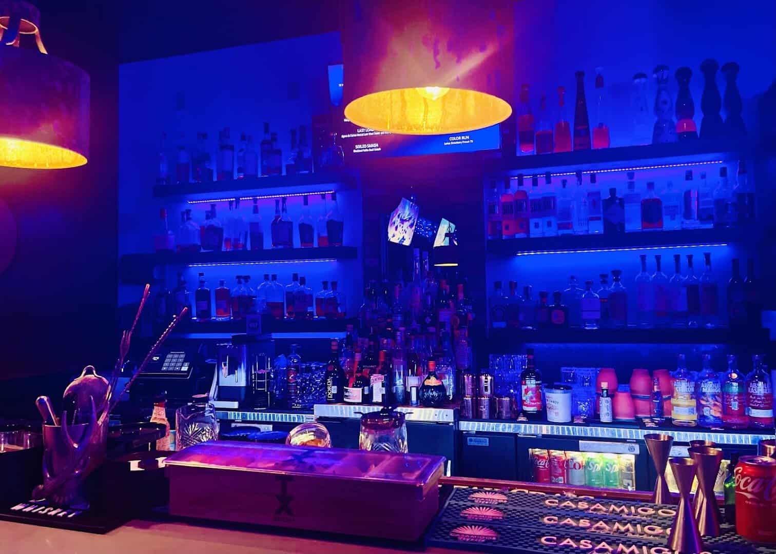 The neon-lit back bar and liquor bottles at Dirty Laundry in Fort Worth