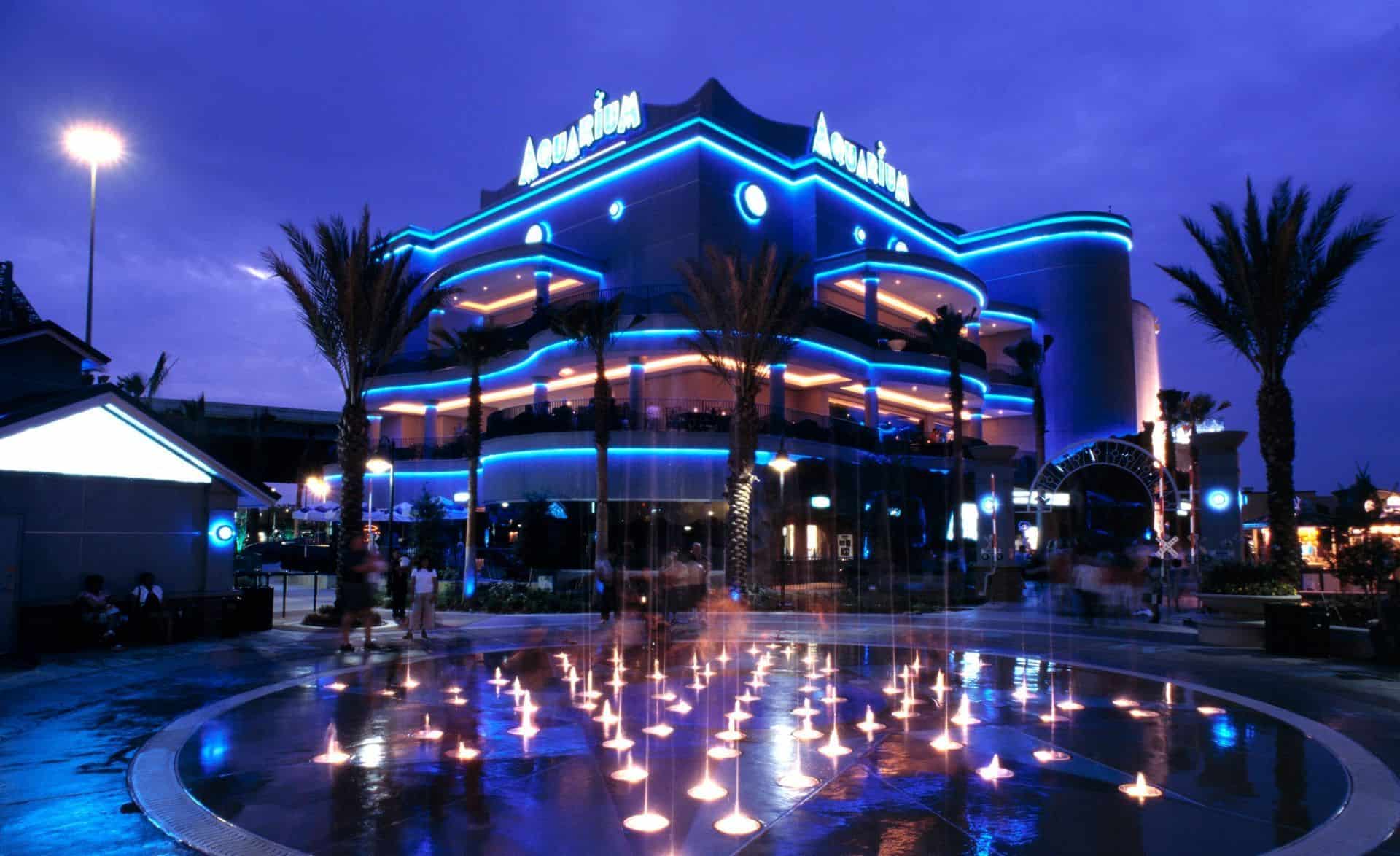 The Downtown Aquarium building lit up at night with fountains in Houston