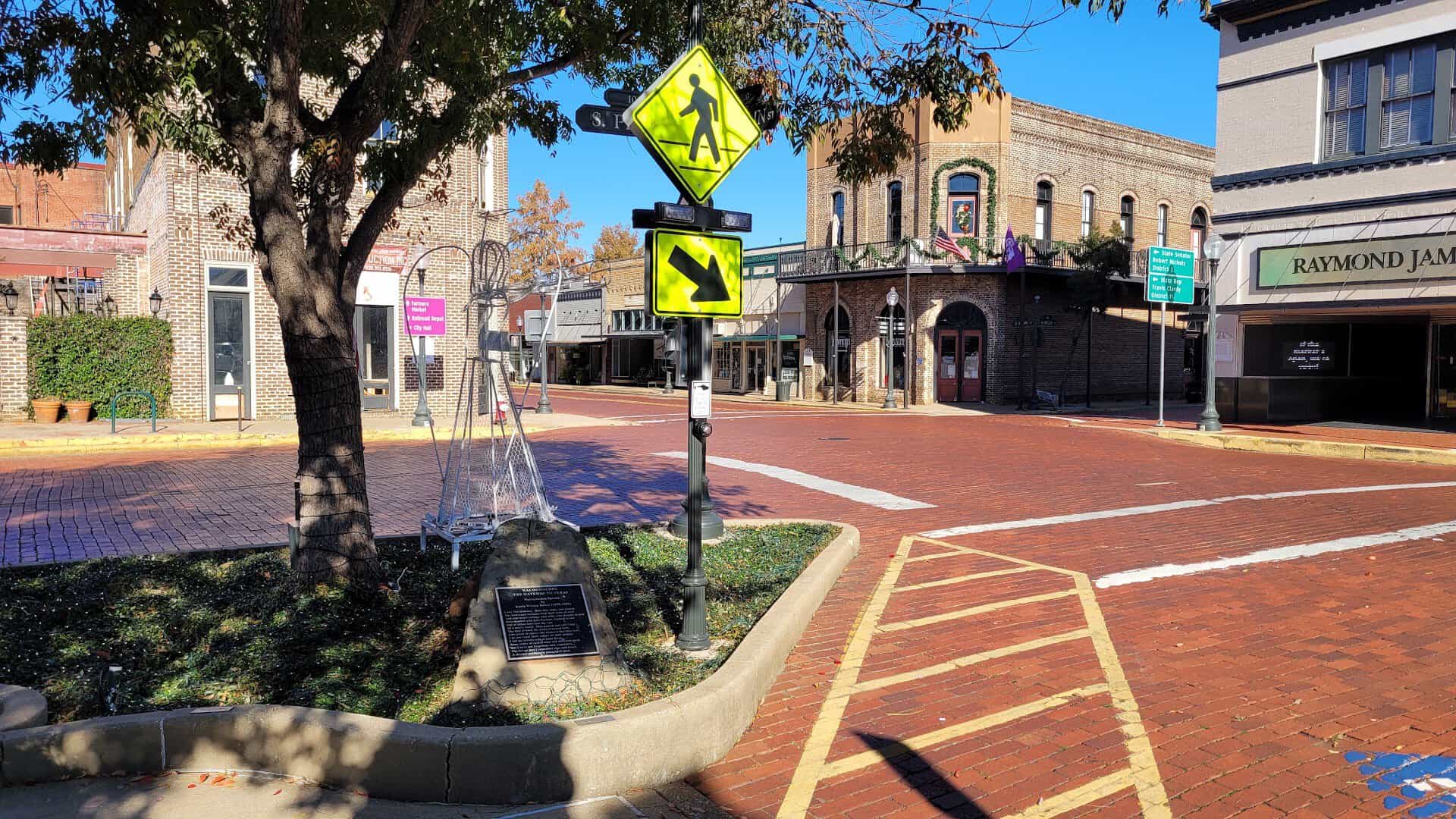 Historic red brick street lined with storefronts in downtown Nacogdoches, Texas