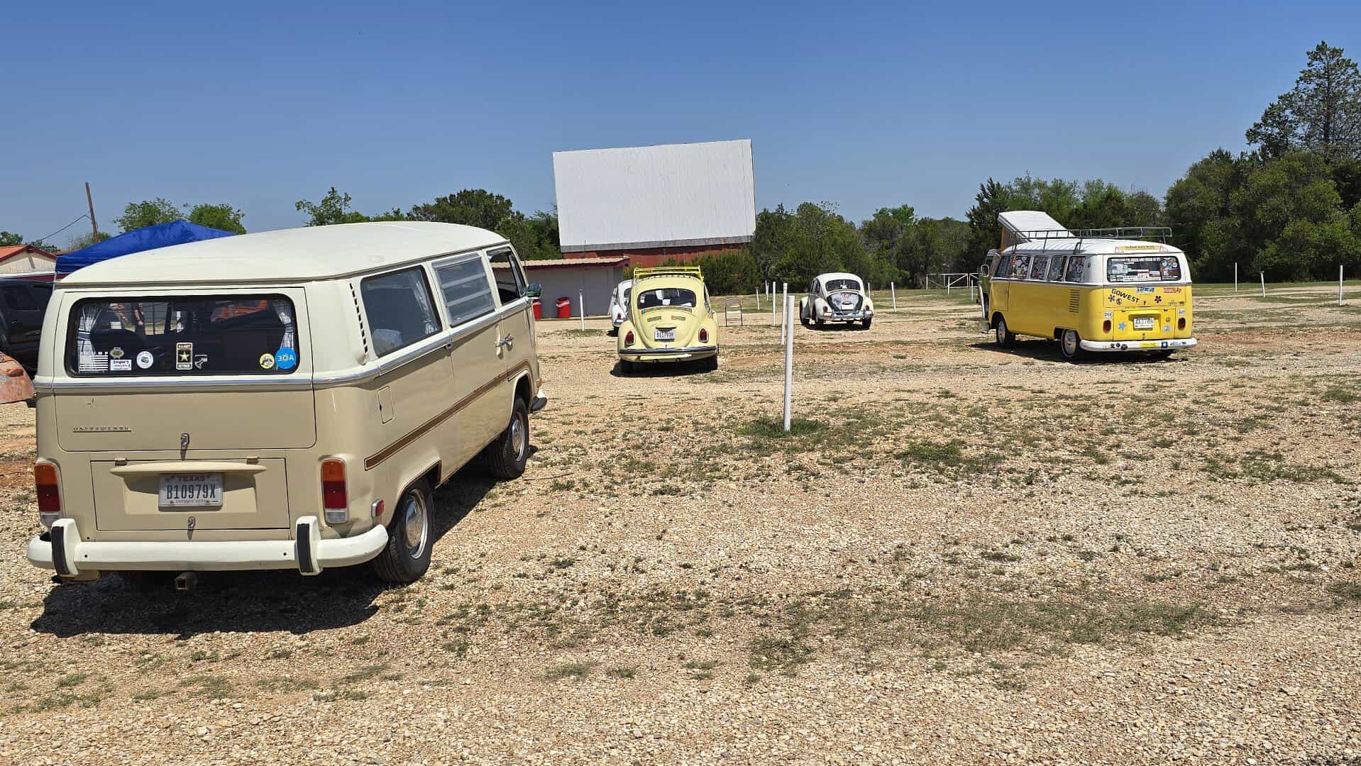 Vintage vans and cars parked facing the screen at The Last Drive-In Picture Show in Gatesville, Texas