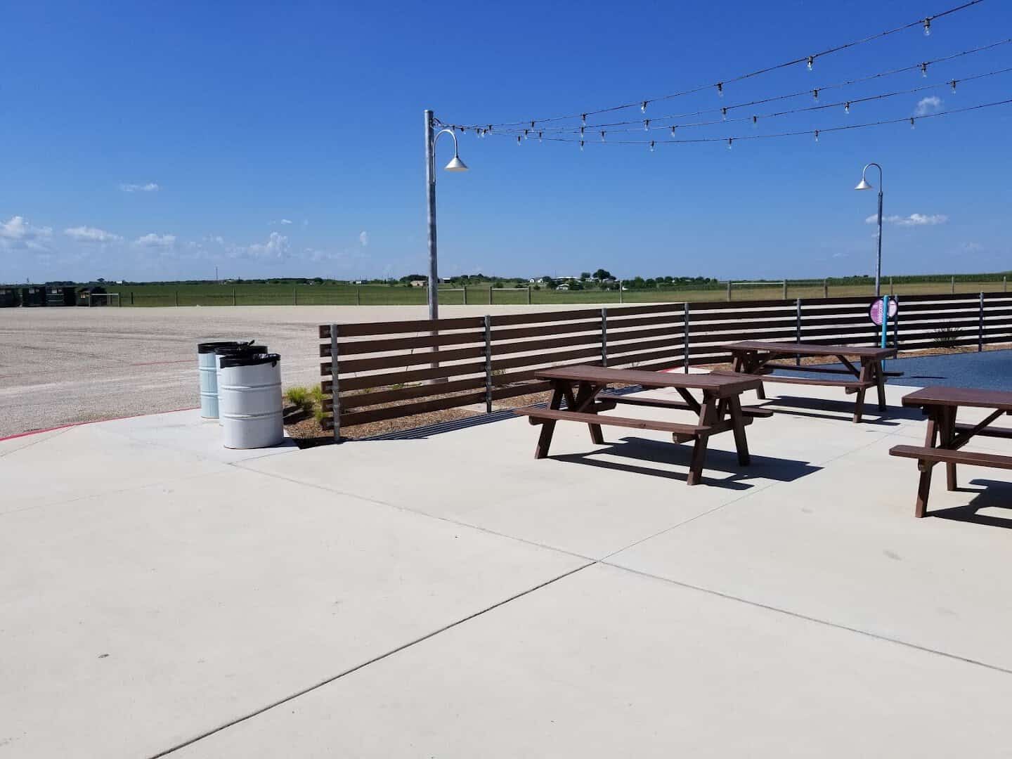 Picnic tables under string lights beside the open field at the New Braunfels drive-in