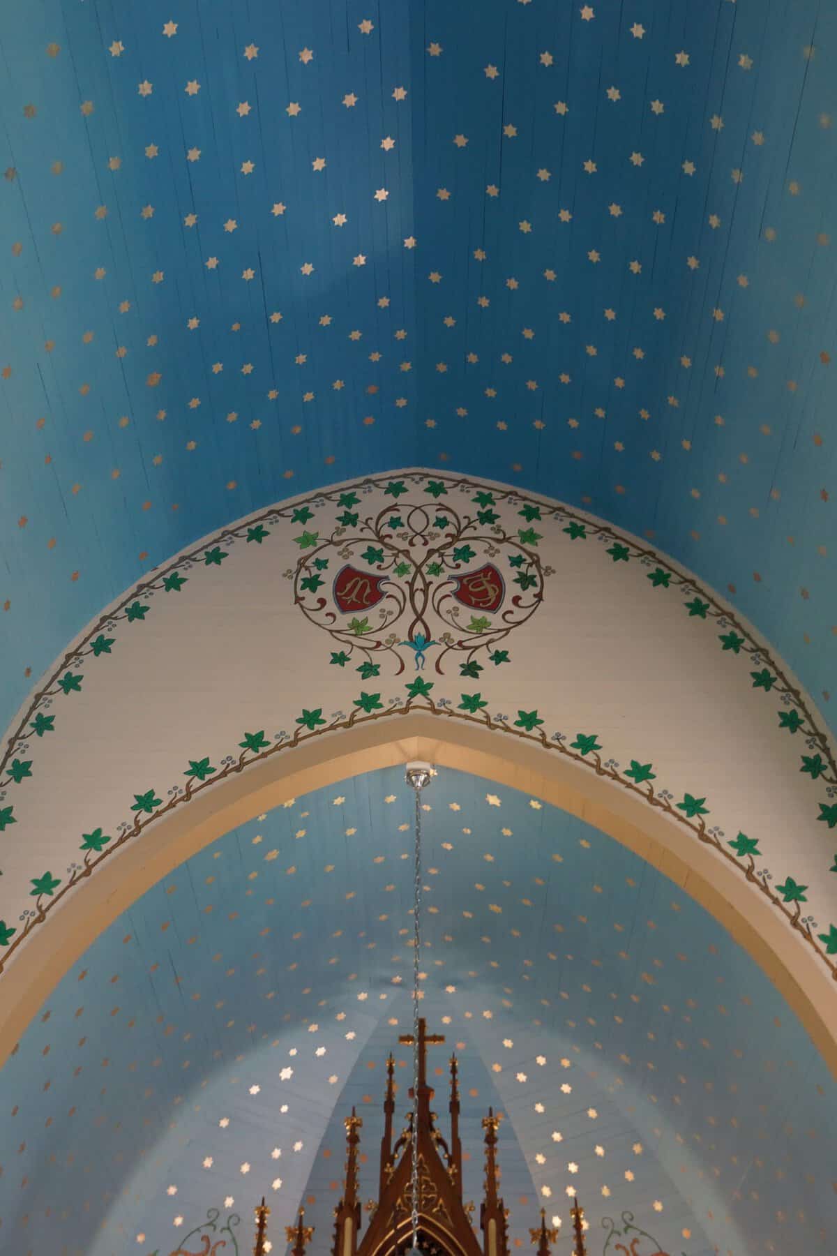 Sky-blue vaulted ceiling covered in gold stars and painted green leaves inside the Dubina painted church in Texas