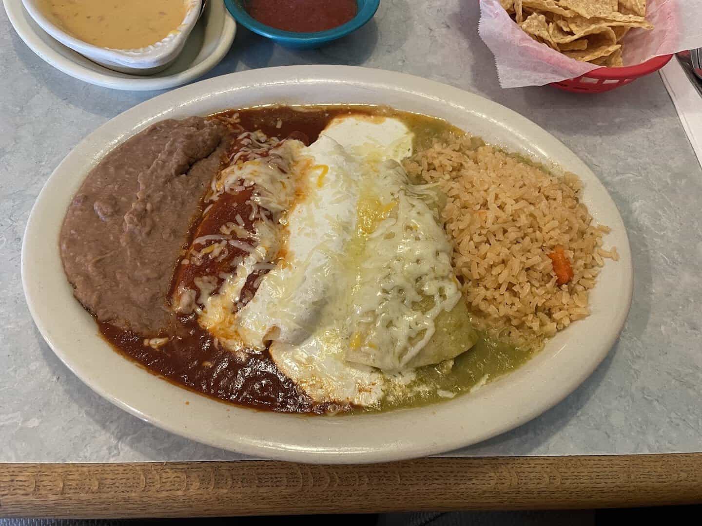 Enchiladas in dark mole sauce with crema, rice and beans at El Jacalito in Austin, Texas