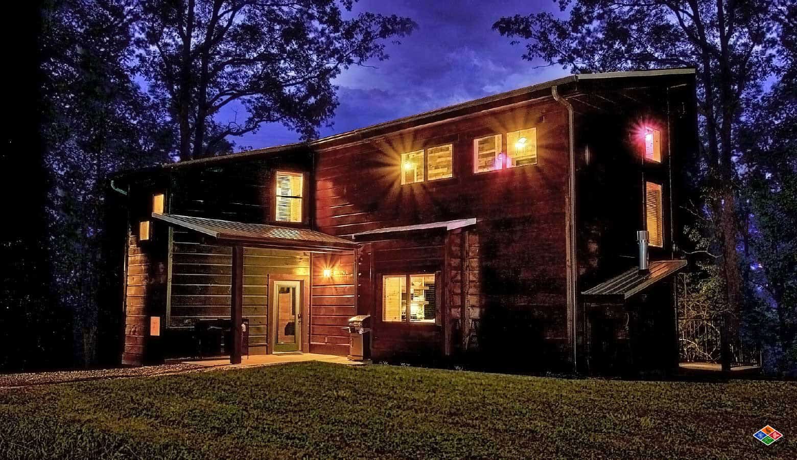 Log cabin exterior lit up at dusk at Elk Springs Resort in Gatlinburg, Tennessee