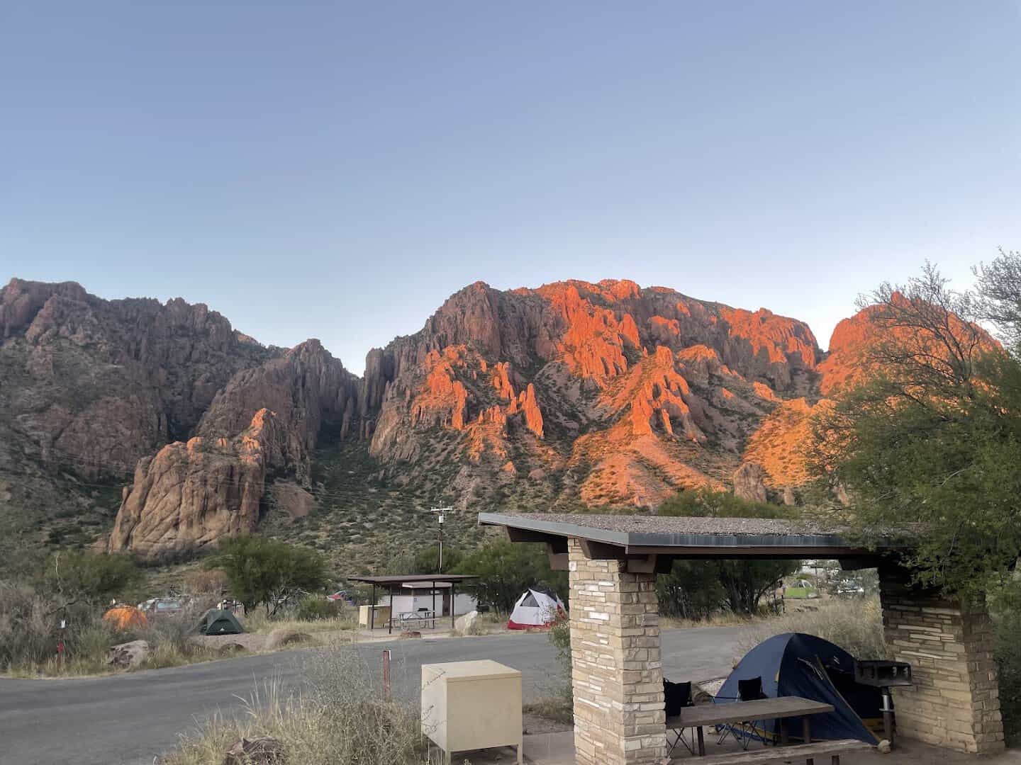 Last evening light striking the Chisos Basin rim above a campsite shelter