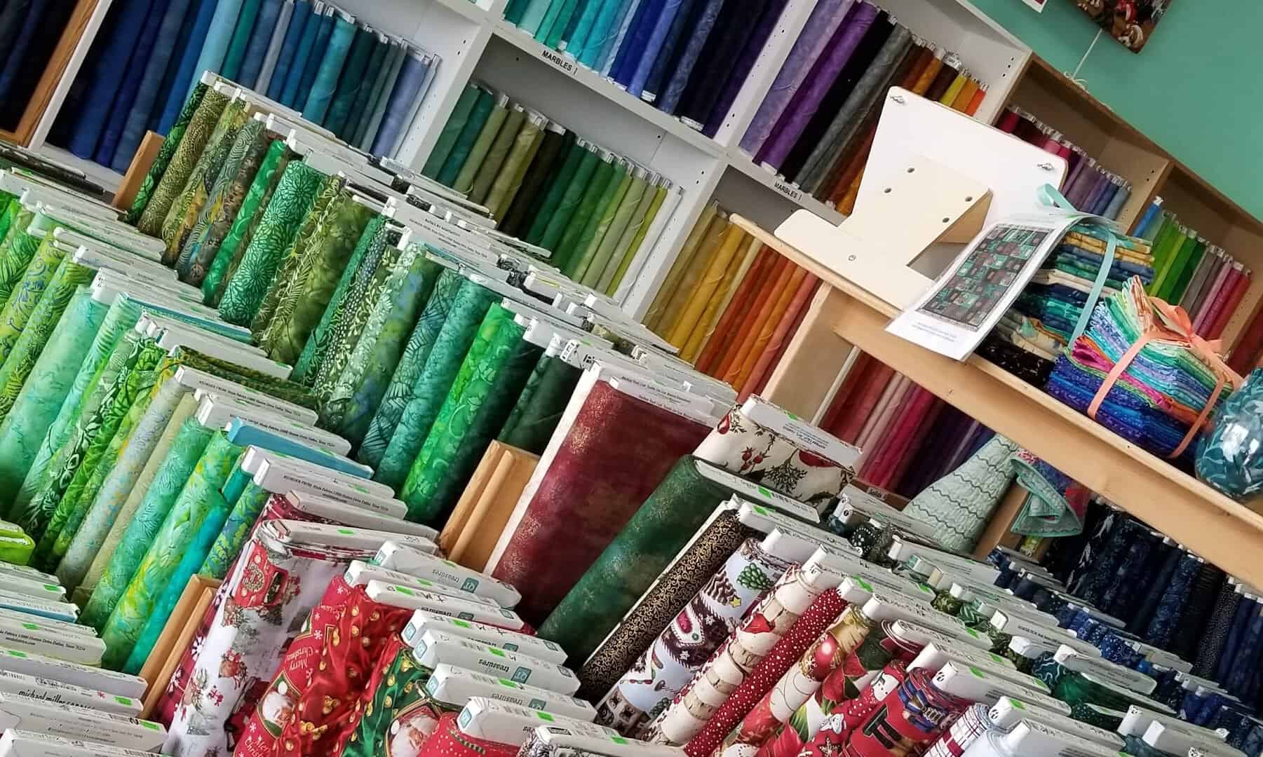 Rows of quilting cotton bolts sorted by color at Quilt Country in Lewisville, Texas