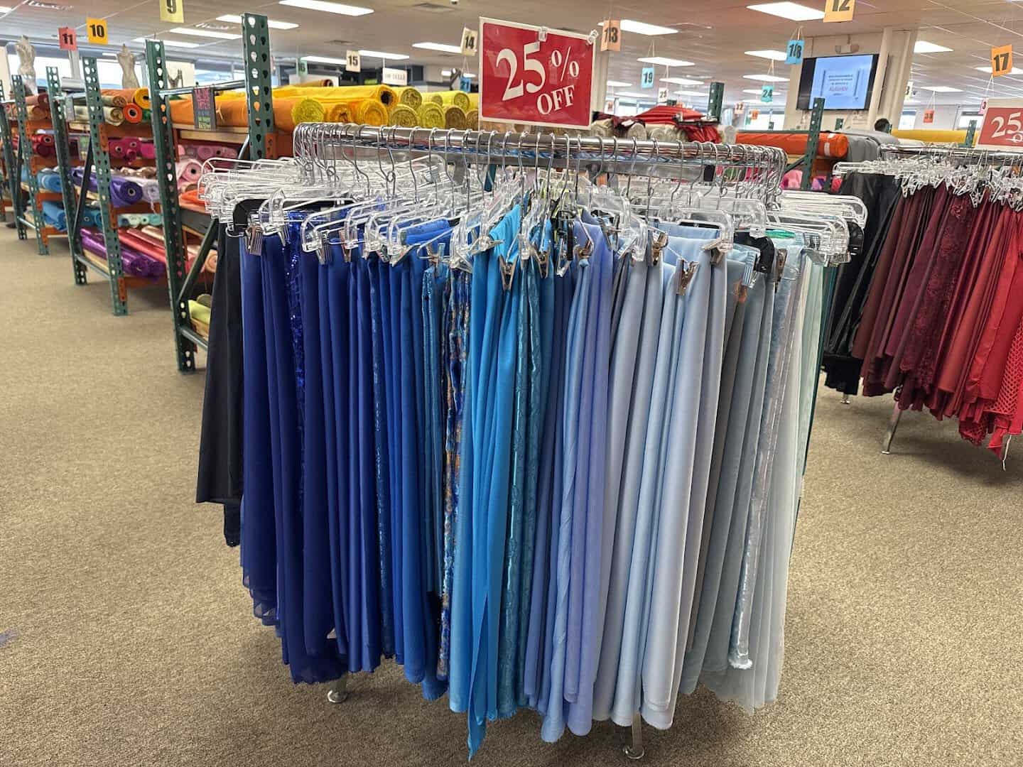 Aisle of colorful hanging fabrics at Fabrictopia in Houston