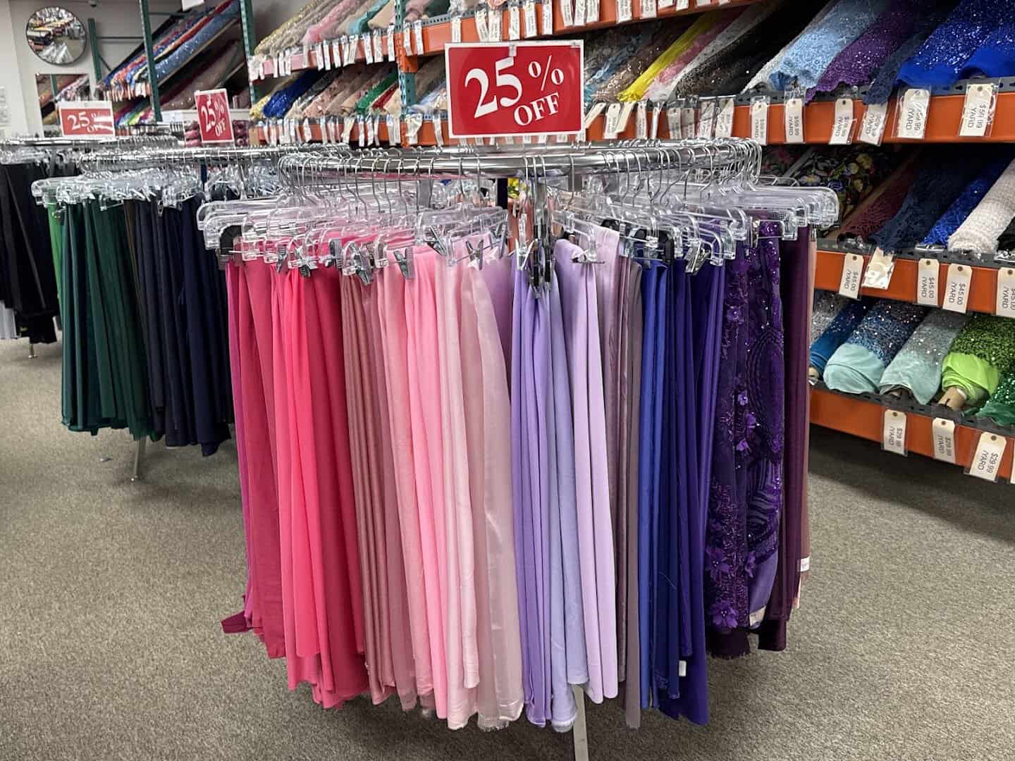 Rack of formal dress fabrics with a discount sign at Fabrictopia in Houston