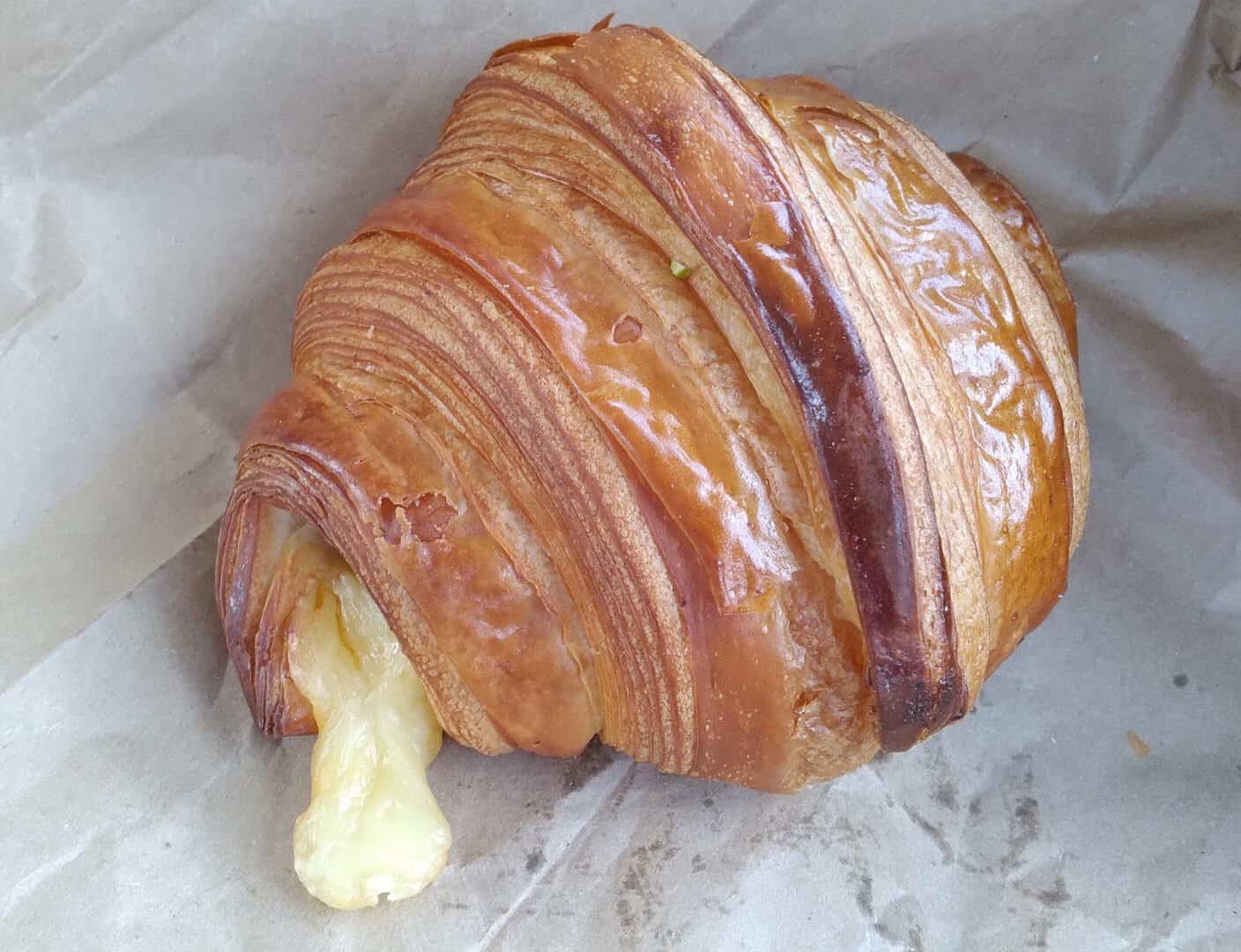 A golden, flaky laminated croissant at Artisana Bread in Houston, Texas