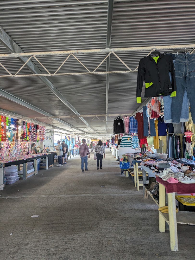 Shoppers walking a crowded aisle of vendor stalls at 77 Flea Market in Brownsville, Texas